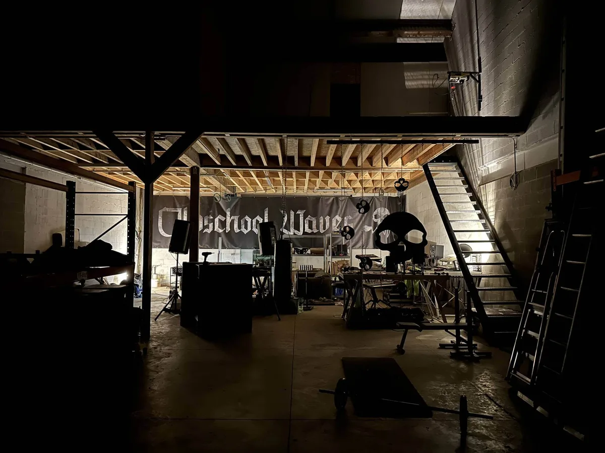 De loods van Oldschool Waves in gedempt licht, groot doek met het logo op de achtergrond